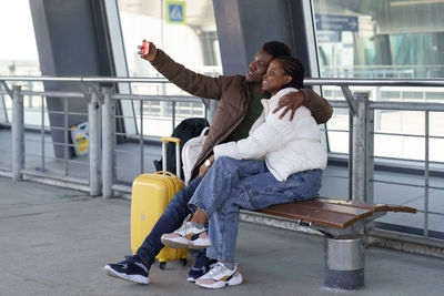 Happy couple of tourists take selfie at airport after arrival, loving african man and woman travel