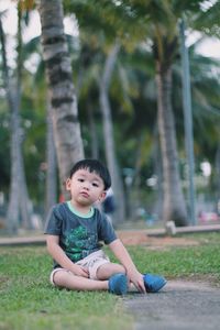Boy sitting on grass in park