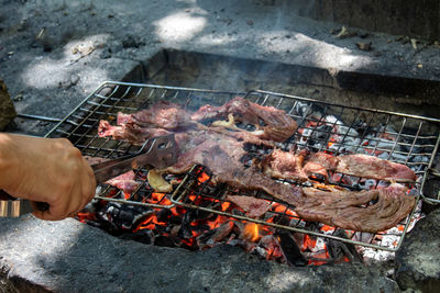 A hand cooking veal on the fire