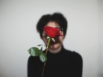 Rose in front of young woman against white background