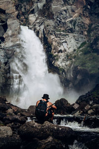 Man surfing on rocks against waterfall