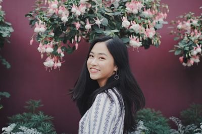 Beautiful young woman standing by flower tree