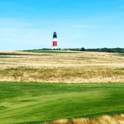 Lighthouse on field against sky