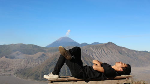 Man lying on mountain against sky