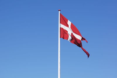 Low angle view of danish flag against blue sky