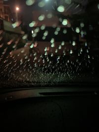 Raindrops on illuminated car windshield at night