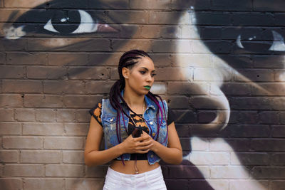 Young woman standing against wall