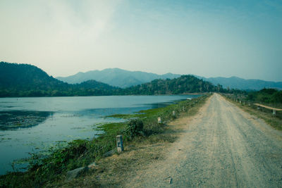 Scenic view of road by mountains against clear sky