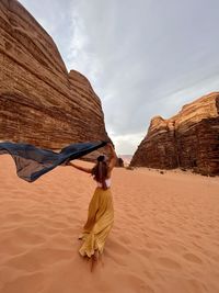 Rear view of woman standing at beach against sky