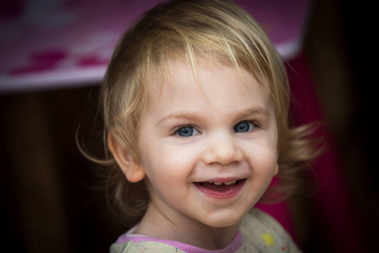 portrait, looking at camera, smiling, blond hair, headshot, child, childhood, one person, happiness, cheerful, toothy smile, cute, human face, close-up, one girl only, gap toothed, children only, human body part, people, front view, human eye, beauty, real people, domestic life, indoors, eye color, day