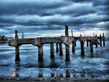 Pier on sea against cloudy sky