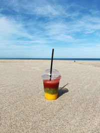 View of drink on table at beach against sky