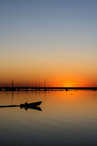 Silhouette boat in sea against sky during sunset