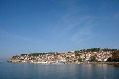 Townscape by sea against blue sky