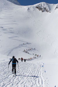 Rear view of hiker skiing on snow covered landscape