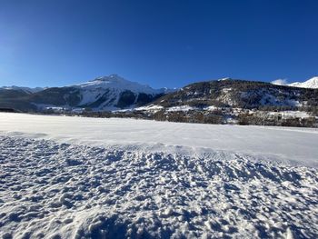 Scenic view of snowcapped mountains against clear blue sky