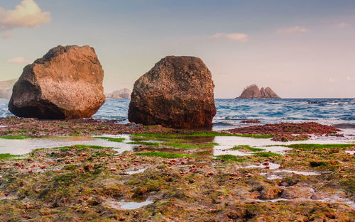 Rocks on sea shore against sky