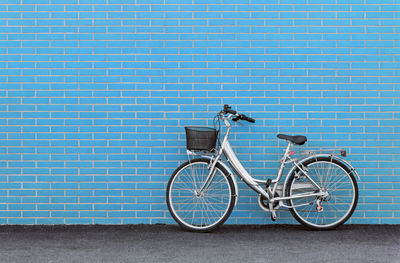 Bicycle parked against blue wall