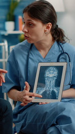 Nurse showing medical xray on digital tablet at clinic