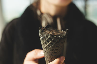 Midsection of woman holding ice cream cone at home