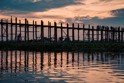 Pier on lake against sky during sunset