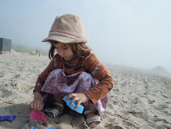 Girl playing sand toys at the beach. foggy day