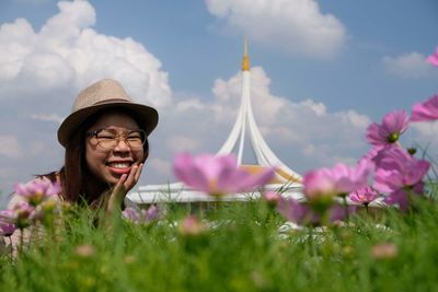 Portrait of smiling woman with pink flowers against sky