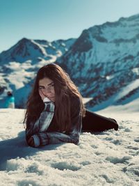 Portrait of woman lying on snow covered field