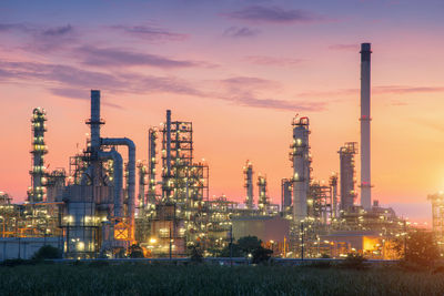 Illuminated factory against sky during sunset