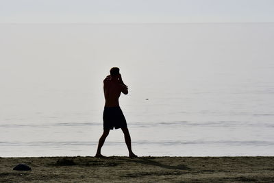 Full length of man standing on beach against sky