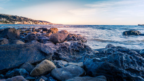 Rocks on beach against sky during sunset