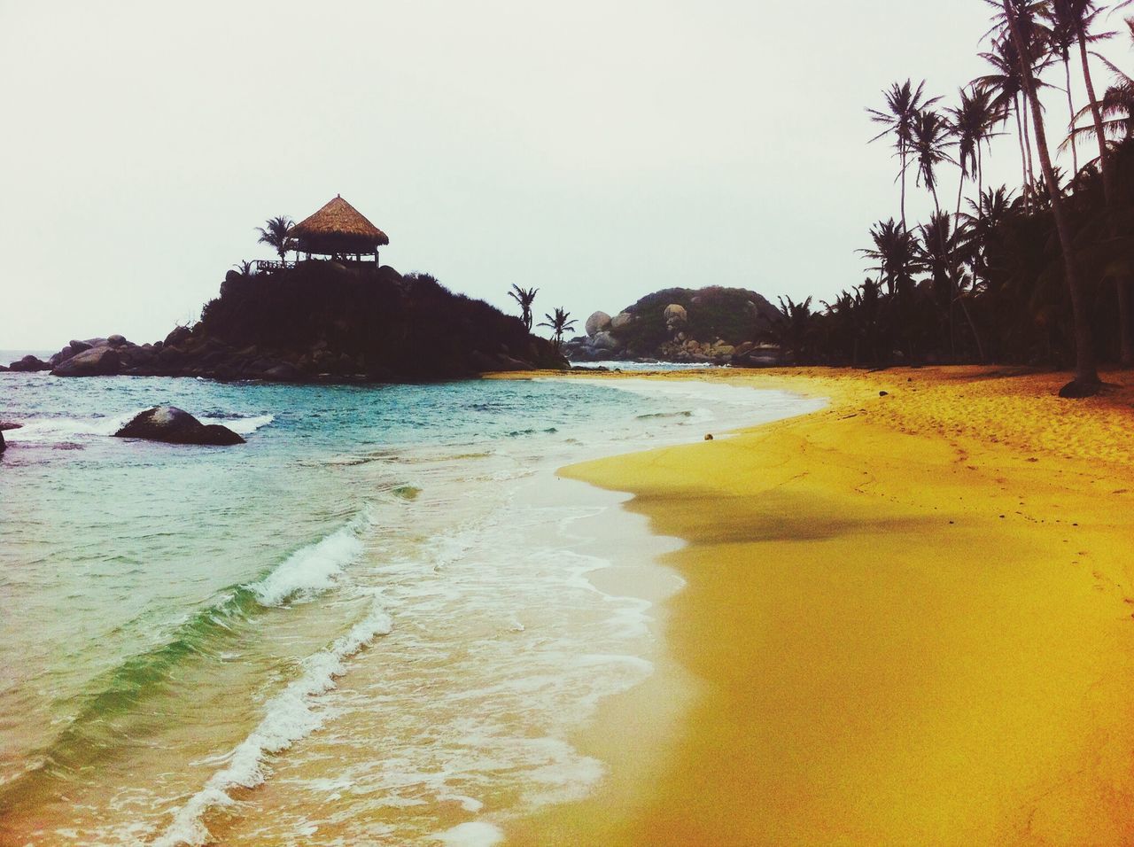 water, sea, beach, tranquil scene, scenics, tranquility, shore, built structure, clear sky, beauty in nature, sand, architecture, nature, building exterior, sky, horizon over water, idyllic, coastline, tourism, tree