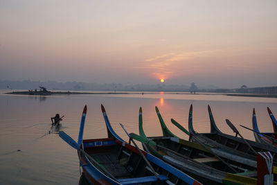 Boats moored on sea against sky during sunset