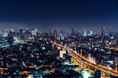 Illuminated osaka cityscape against clear sky at night