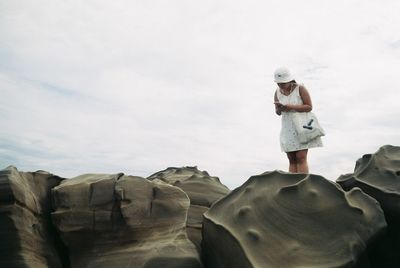 Man standing on rock against sky