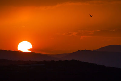 Scenic view of silhouette mountains against orange sky