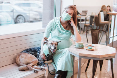 Woman with dog sitting on table