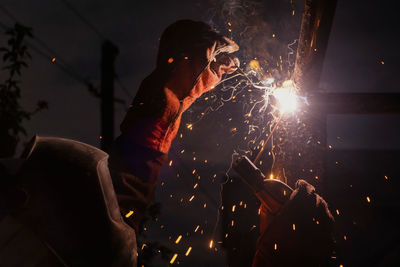 A man is welding a piece of metal in the dark