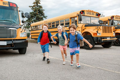 Happy caucasian children boys and girl kids students running near yellow school bus. education 