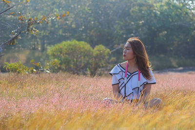 Woman sitting on field against sky