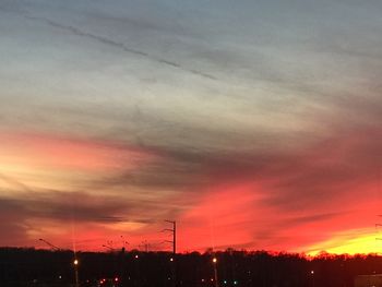 Silhouette electricity pylon against dramatic sky during sunset