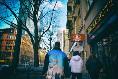 Rear view of people walking on street amidst buildings
