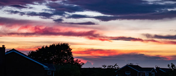 Silhouette trees and buildings against sky during sunset