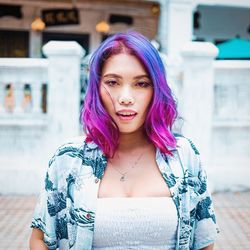 Portrait of beautiful woman standing against purple outdoors