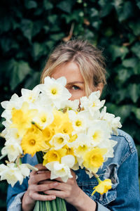 Portrait of woman holding yellow flowering plant