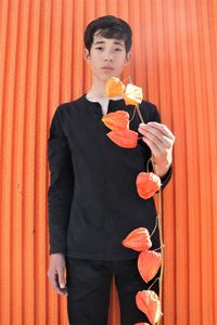 Mid adult man standing against orange wall