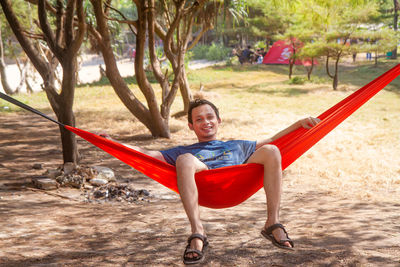 Young happy asian man relaxing lying in hammock person