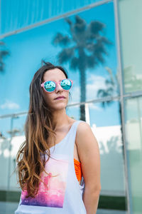 Portrait of young woman wearing sunglasses standing outdoors