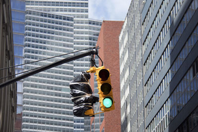 Low angle view of road signal and buildings against sky in city