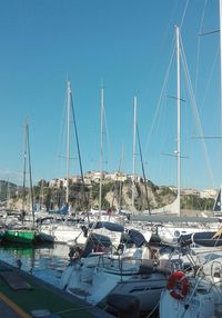 Sailboats moored at harbor against clear blue sky